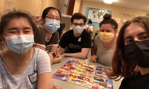 students surrounding a completed jigsaw puzzle with masks on